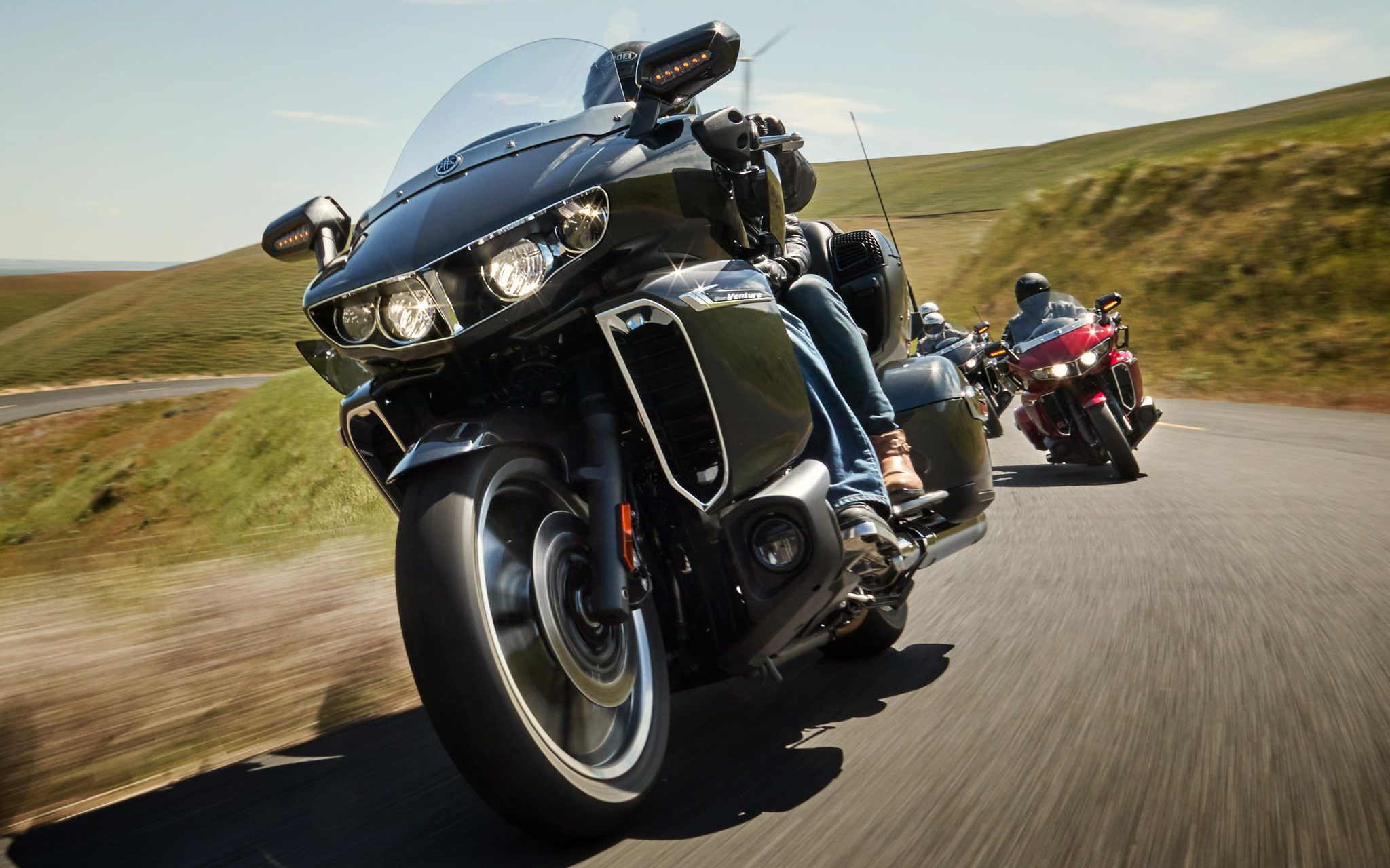Group of riders cruising through grassy hills on Yamaha Star Venture Motorcycles