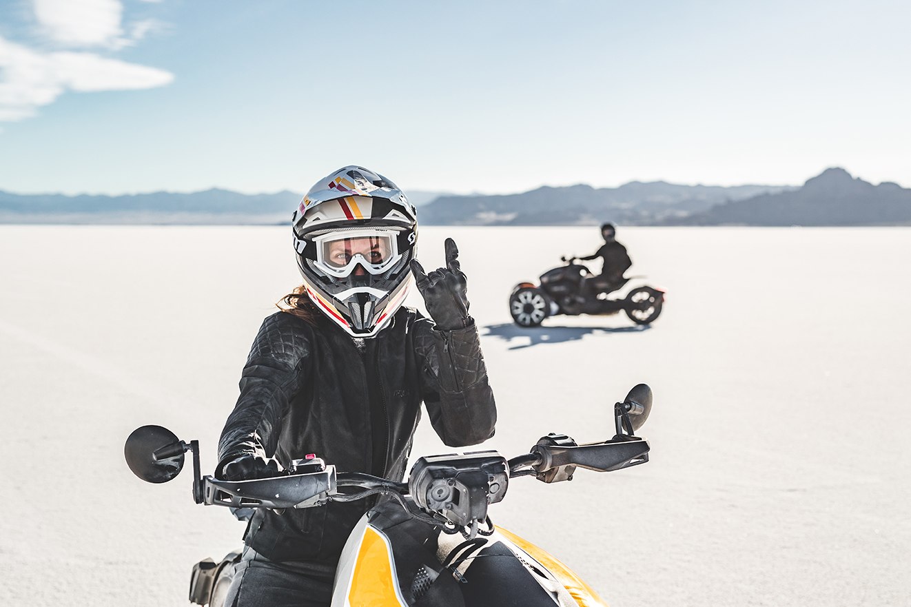 close up of rider rocking out on Can Am Ryker with blurry second rider in the desert background