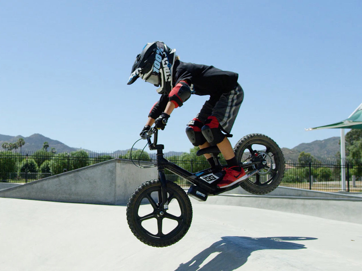 Youth taking jump at skatepark on Stacyc electric bicycle
