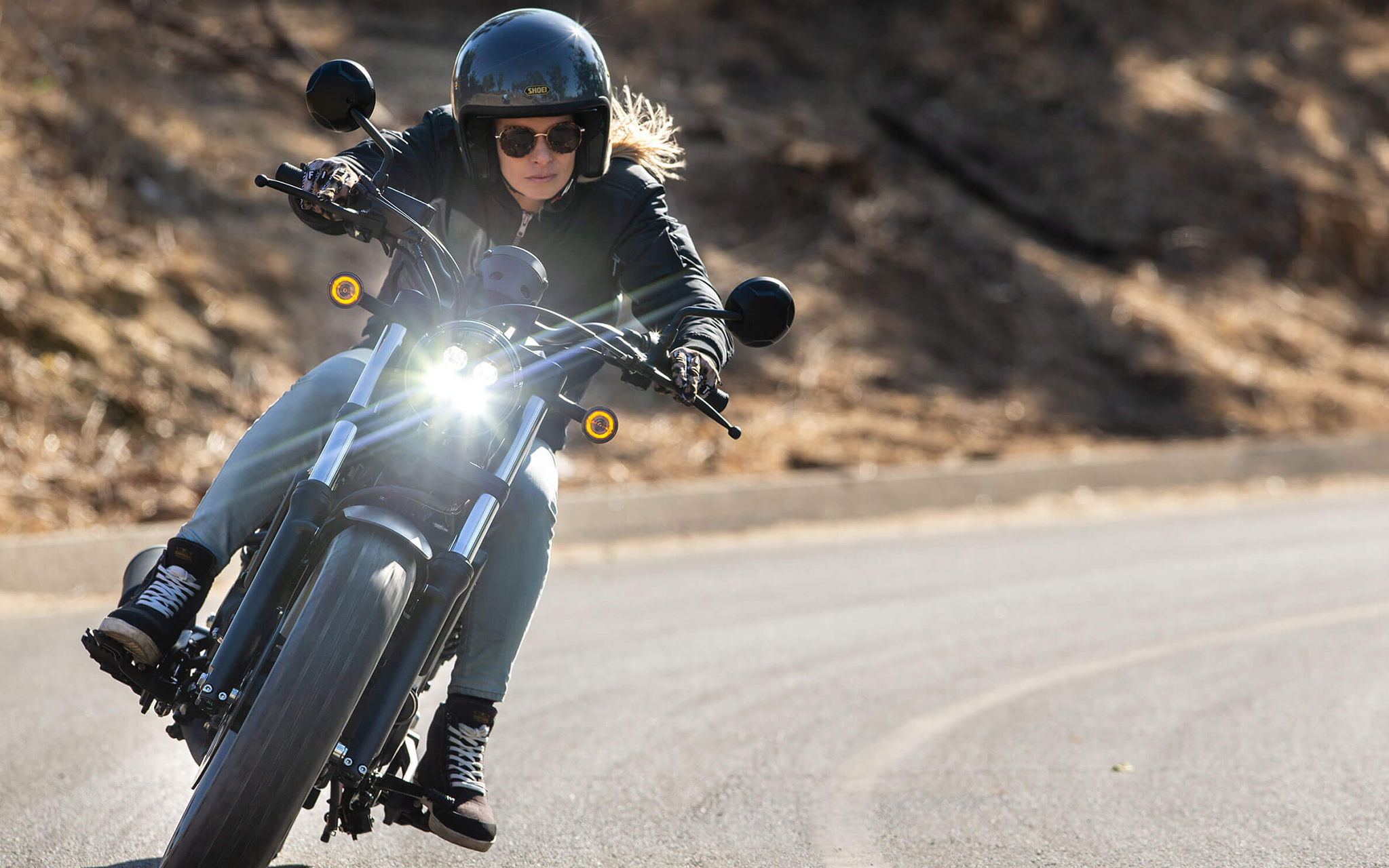 Stylish woman on Rebel 500 turning towards us