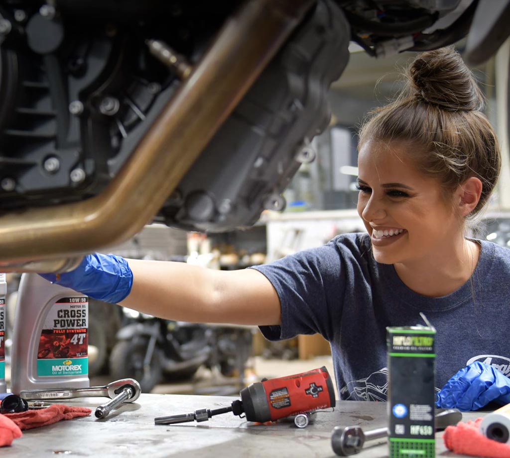 Service technician changing oil on motorcycle