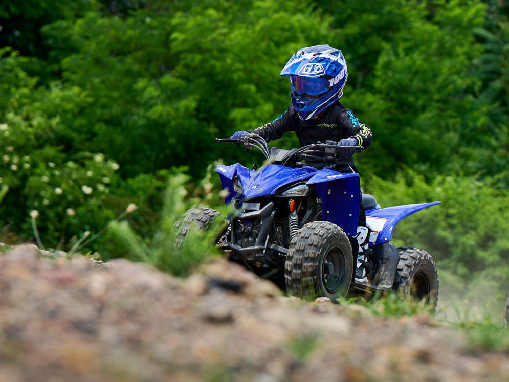 Youth riding Yamaha Raptor 90 up hill