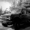 Black & white photo of white vinyl on front window of Ford Bronco