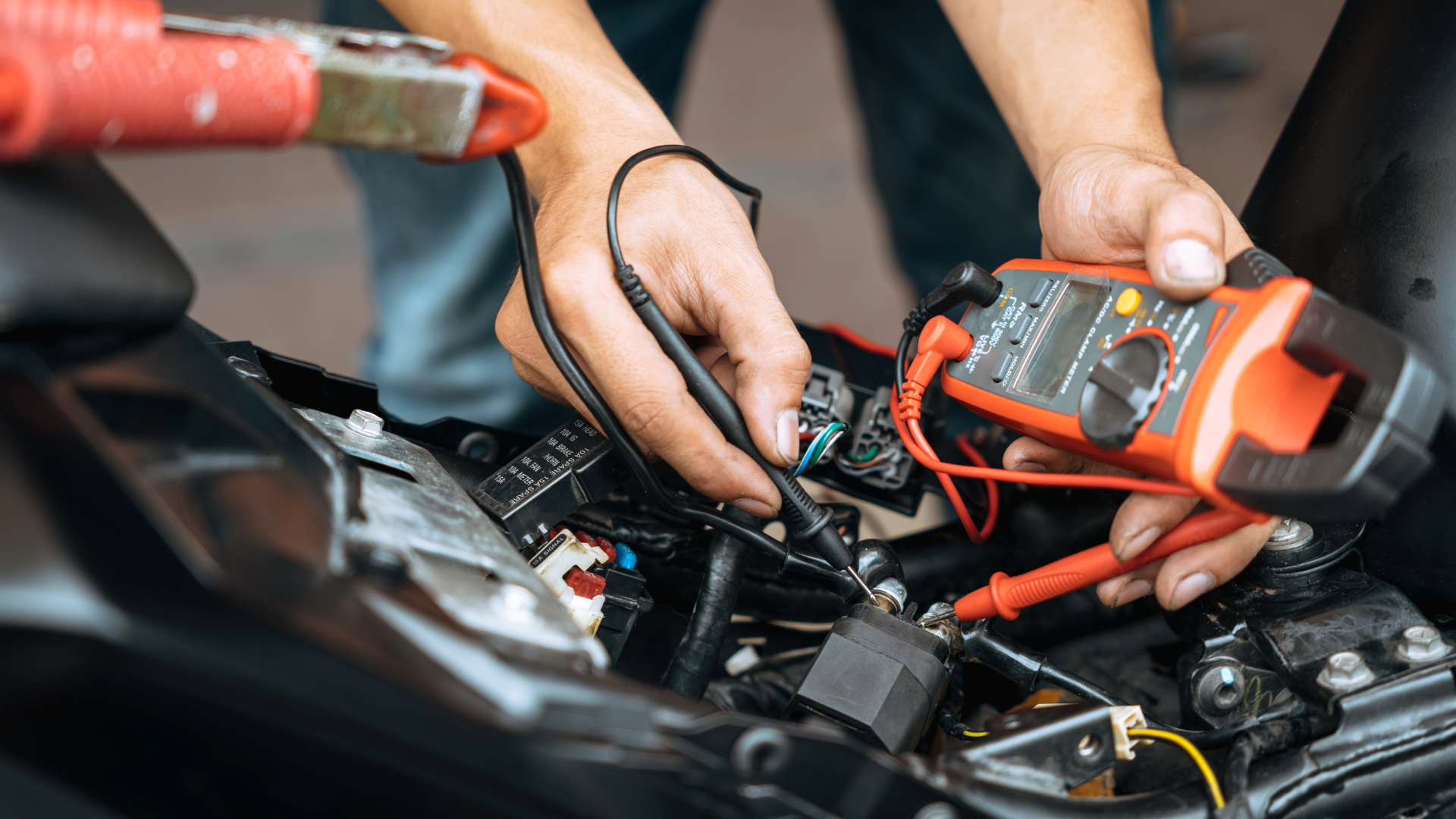 Testing motorcycle battery voltage with a multimeter during spring pre-ride inspection.